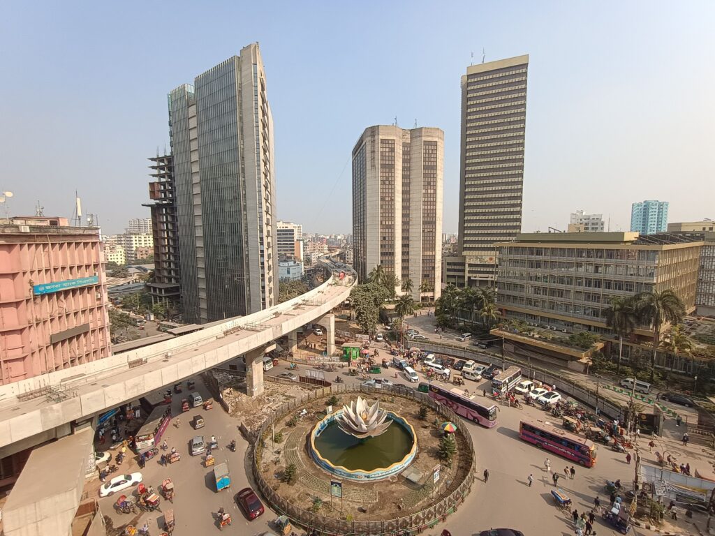 Aerial view of Dhaka city center featuring skyscrapers, metro rail, and bustling streets.